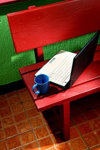 木制长凳上的笔记本电脑和咖啡杯