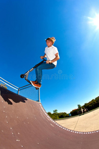 男孩在溜冰场用他的特技滑板车跳跃