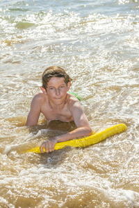 男孩在海里玩他的冲浪板玩得很开心