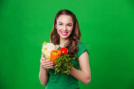 美丽的女人拿着新鲜健康的食物。 在绿色背景上