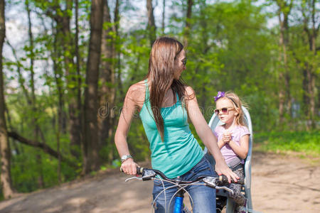 快乐的妈妈和小女儿在公园里骑自行车