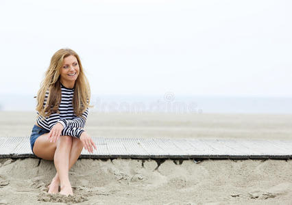 坐在海滩上微笑的金发女郎