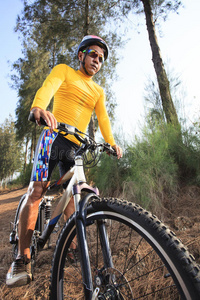 年轻男子骑山地自行车在丛林轨道上用于体育运动