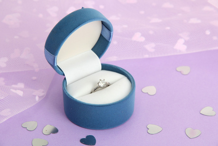 美丽的盒子与紫色背景上的结婚戒指