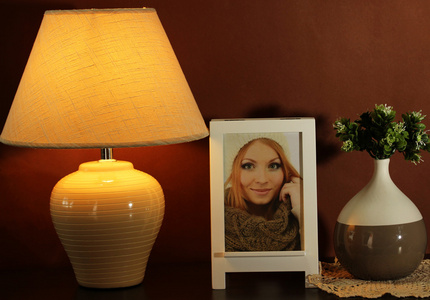 白色相框和褐色的墙壁背景上的木桌上的灯