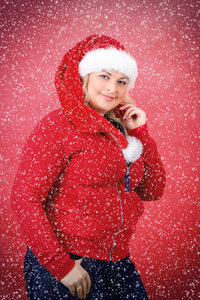 在红色圣诞老人帽子微笑与雪花的快乐漂亮女人