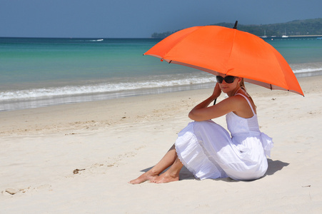 在沙滩上的橙色雨伞的女孩照片