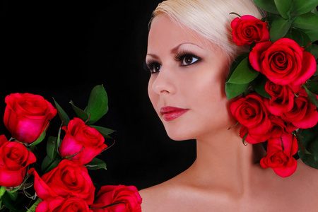 美丽的金发年轻女子与红玫瑰在黑色的背景，时尚肖像