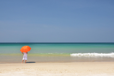 在沙滩上的橙色雨伞的女孩