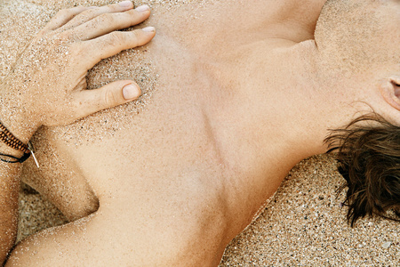 金黄的沙滩上享受日光浴的一名男子的身体部分细节
