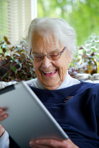 快乐老年妇女使用绘图板和笑
