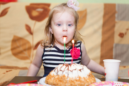 白种人的小女孩两个耳朵吹生日蛋糕上的蜡烛