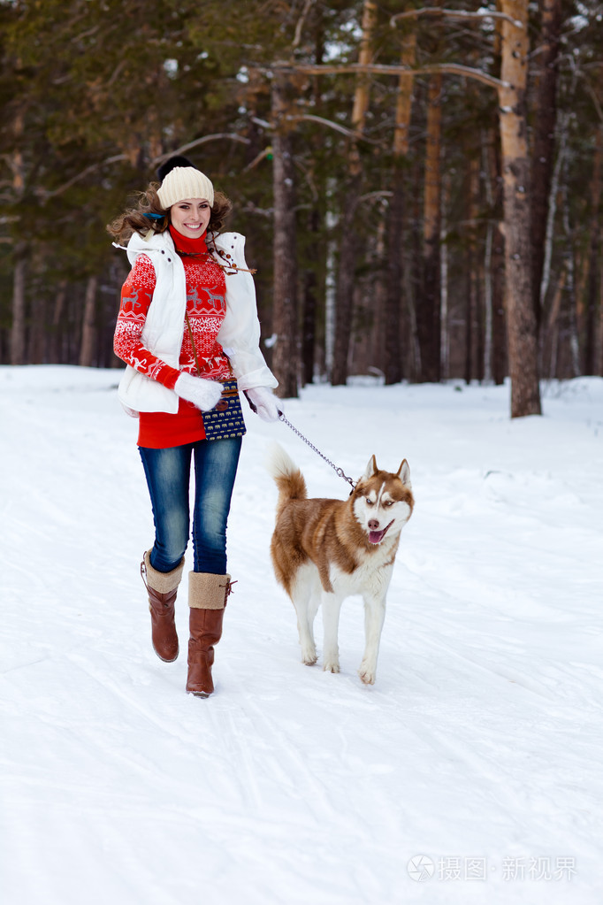 快乐的女人玩冬季森林的西伯利亚爱斯基摩狗