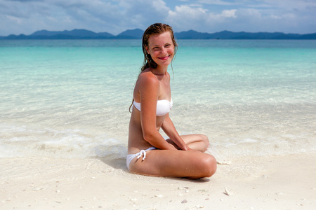 美丽的年轻女子穿着比基尼在阳光明媚的热带海滩相关