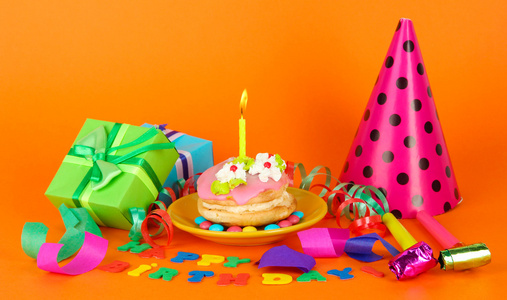 七彩生日蛋糕与蜡烛和礼品的橙色背景