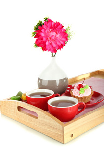 杯茶与花和蛋糕上孤立在白色的木托盘