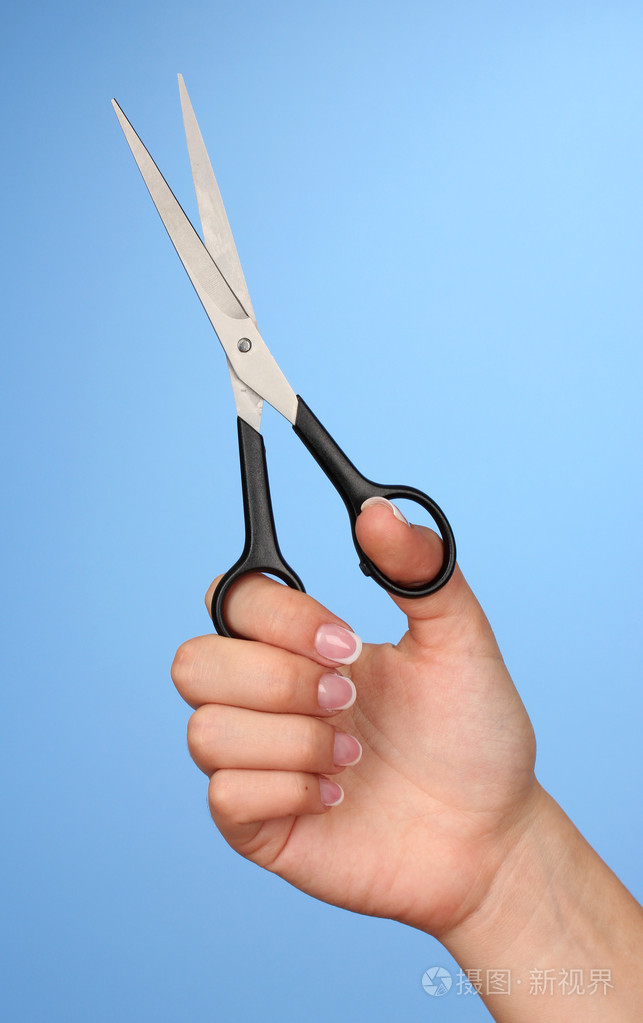 女性手用颜色背景上的剪刀