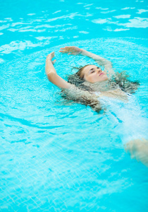 年轻女子在游泳池中游泳