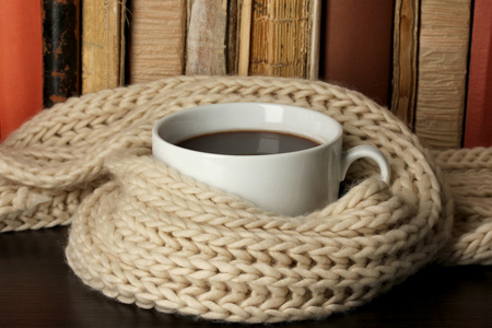 杯咖啡裹着围巾的书背景上
