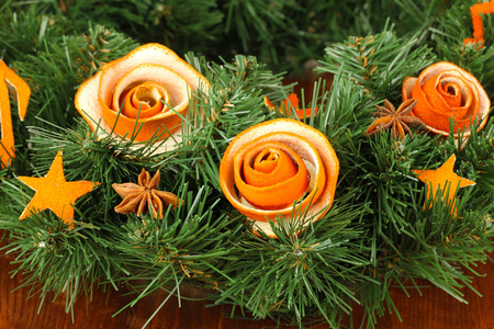圣诞花环装饰着干桔皮木桌上的玫瑰