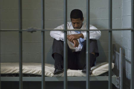男子坐在监狱牢房的床上