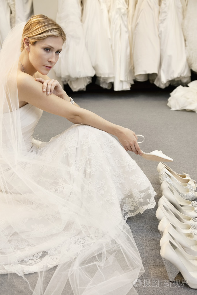 美丽的年轻女子在婚纱店鞋类选择与混淆