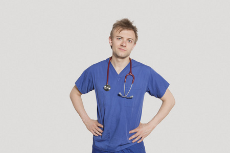 男性外科医生用双手叉腰站在灰色背景的肖像