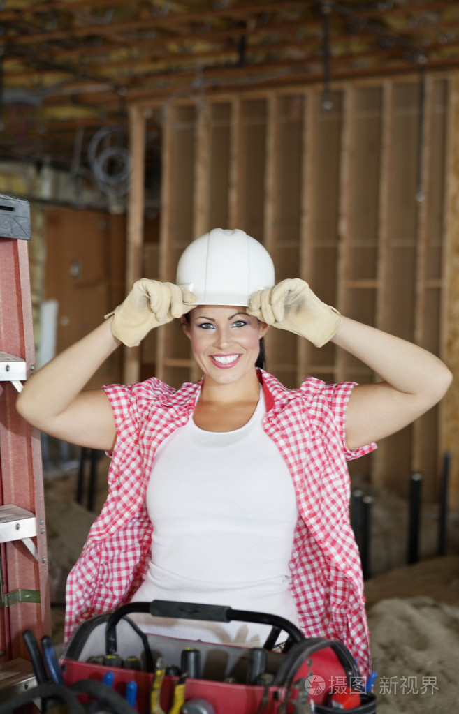 在建筑工地戴安全帽的快乐年轻女性承包商的肖像