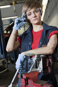 在车库里戴防护眼镜的年轻女性机械师的肖像