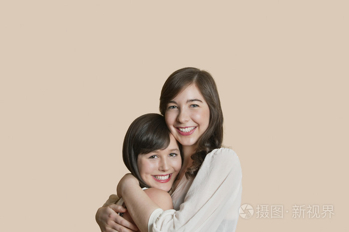年轻女性朋友拥抱在彩色背景的肖像