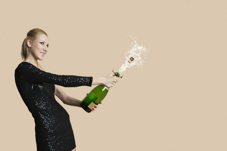美丽的年轻女子 uncorking 香槟瓶在彩色背景