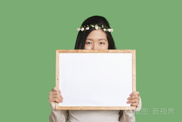 她的脸庞与空白白板上绿色背景年轻女子肖像