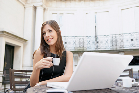 有吸引力的女商人喝咖啡和使用一台便携式计算机