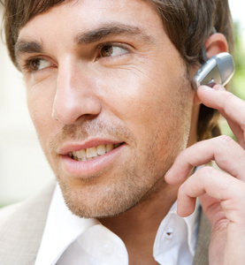 有吸引力的年轻商人使用手免费耳片设备来打个电话