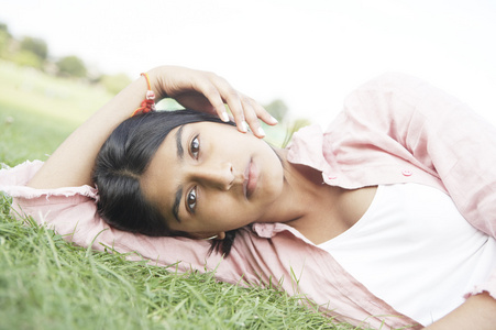印度女孩躺在绿草看看相机