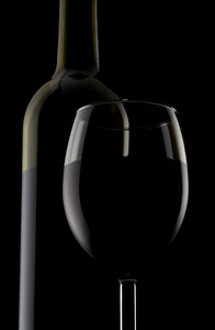 一个玻璃和瓶红酒被隔绝在黑色背景上