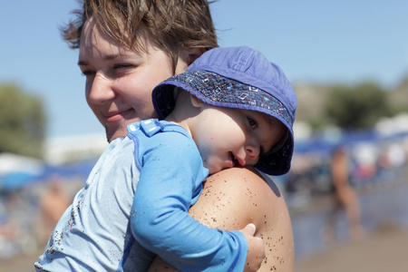 母亲抱着她的儿子在海滩上