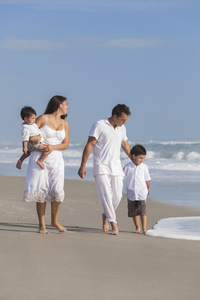 母亲 父亲和儿童家庭走玩在海滩