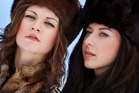 皮草帽子冬季森林中的两个年轻女人