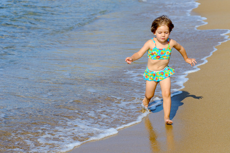 快乐蹒跚学步女孩在海滩上运行