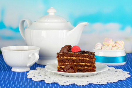 茶壶 杯茶和美味的蛋糕上蓝色自然背景