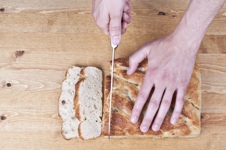 一只手用刀切片面包