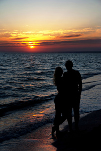 反对日落海滩上的情侣剪影