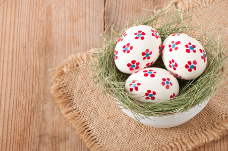 一碗的复活节彩蛋装饰着木桌上的鸟巢