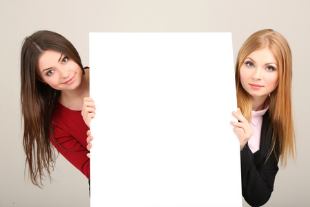 两个商业妇女与灰色的背景上的空白窗体