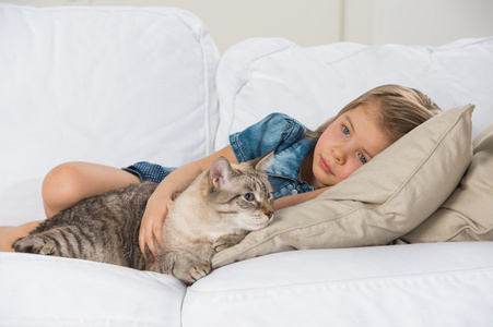 小女孩与她的虎斑猫沙发上铺设