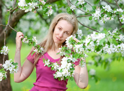 年轻有魅力的女人站在盛开的苹果树附近