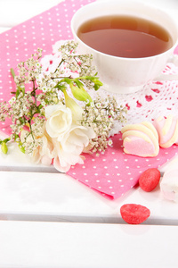 美丽的组成与杯茶和木制野餐表特写上的花朵