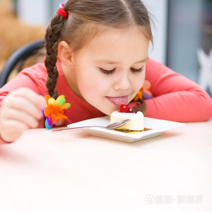 小女孩站在客厅里吃蛋糕