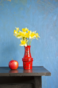 黄水仙在红色花瓶和苹果